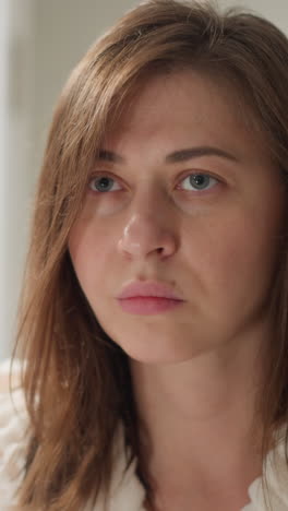 una mujer joven se mira en el espejo examinando la piel facial antes de usar una máscara hidratante. una mujer con una expresión seria mira la piel alrededor de los ojos en cámara lenta