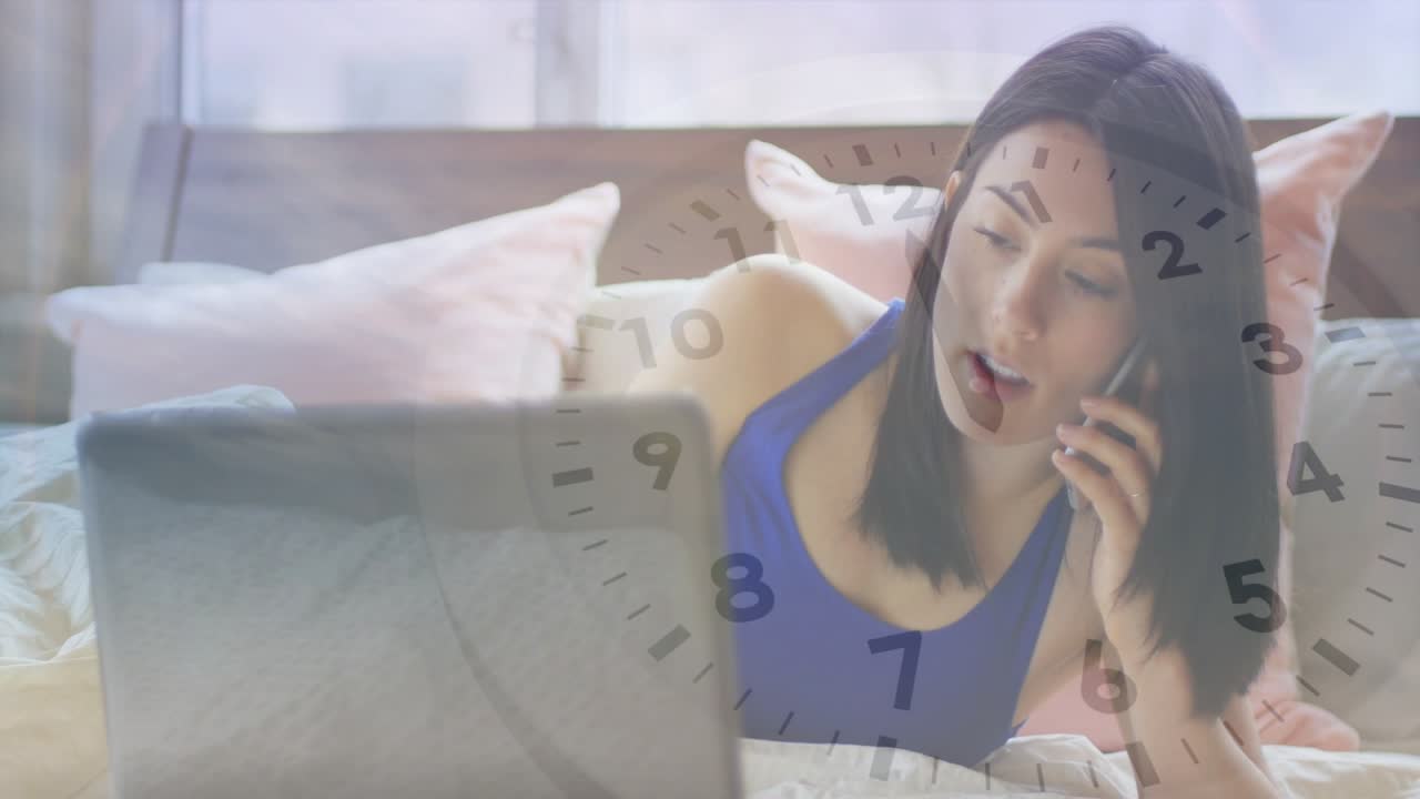 リモートワーク中に電話を受け、時計と月が姿を現す中でノートパソコンに目をやる女性。
