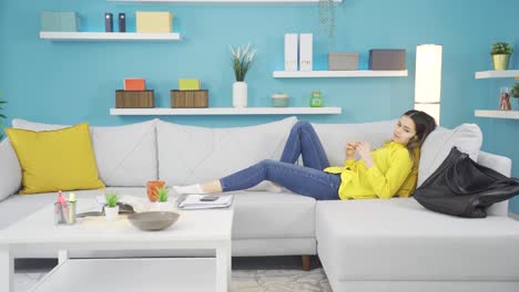 una chica divertida holgazaneando para sacar su teléfono de la mesa en casa.