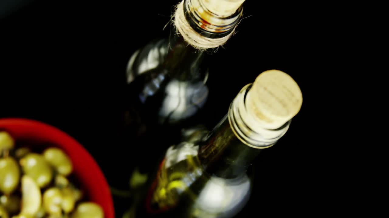 botellas de vino y cuenco de aceitunas con hierbas y especias
