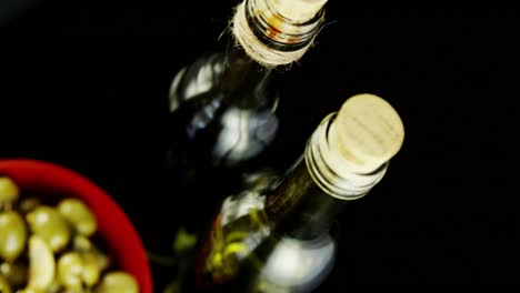 wine bottles and bowl of olives with herbs and spices