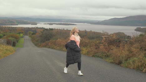 Woman-spinning-with-outreached-arms-overlooking-lake-view