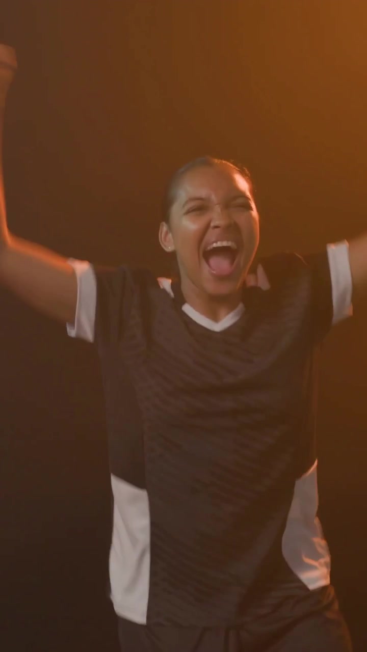 Jubel im Studio, Frau im schwarz-weißen Trikot schwenkt eine Trikolore-Flagge und umarmt eine Teamkollegin beim Feiern.