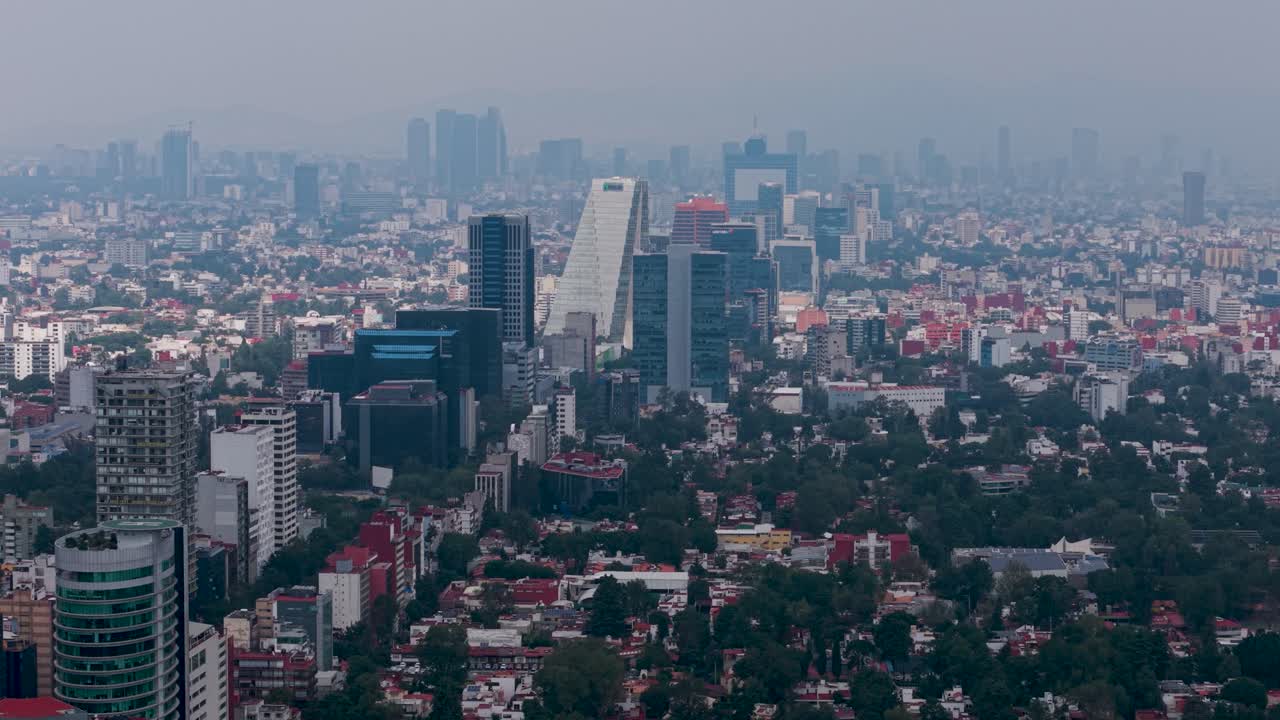 Drone view of CDMX on hazy day featuring avenue with buildings and trees