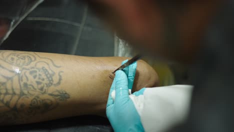 close-up of a tattoo artist working on a client's leg