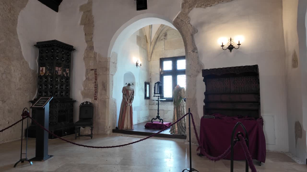 Interior shot of a room inside Corvin’s Castle, showcasing historical dresses displayed alongside rustic wooden furniture