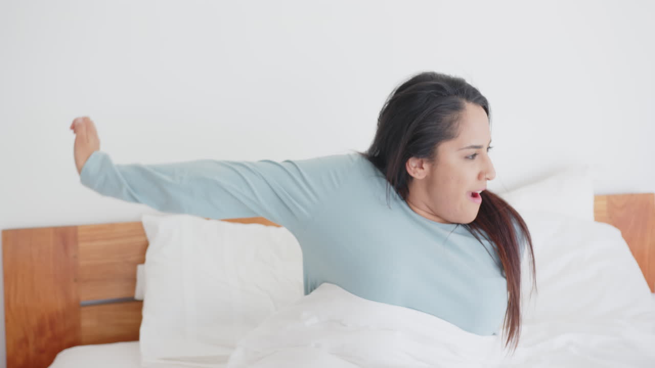 Stretching in bed, asian woman waking up and yawning in morning, at home