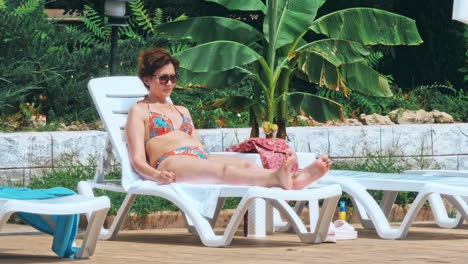 people sitting by the poolside of a resort swimming pool during summer holiday