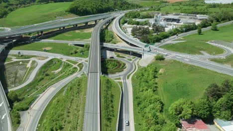 an aerial drone moves forward above an intricate tangle of a highway junction, showcasing cars navigating complex roundabouts and intersecting roads