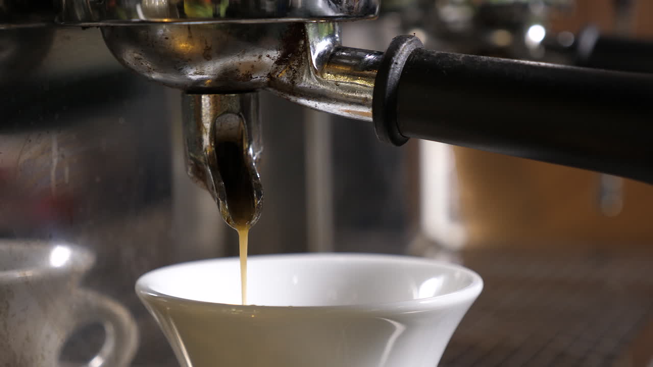 Espresso being brewed into a white cup