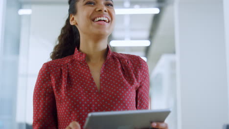 exitosa chica africana buscando la pantalla de la tableta de la oficina. mujer saludando a un colega