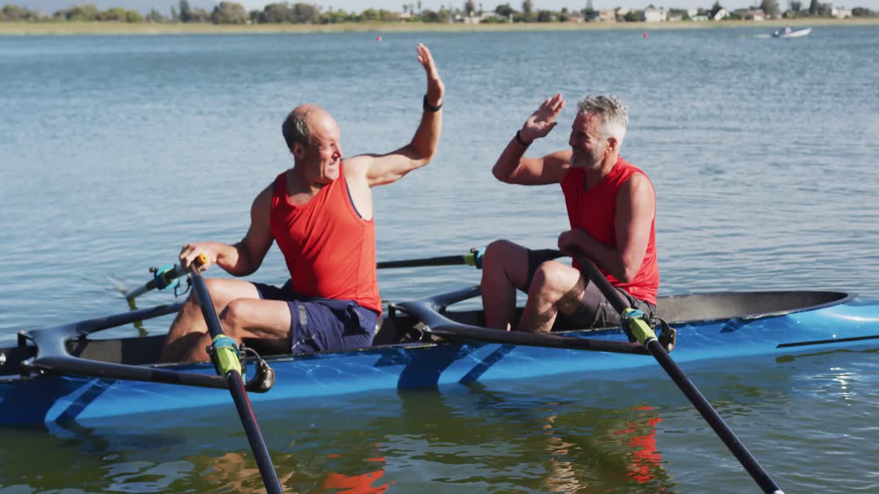 Two senior caucasian men in rowing boat high fiving