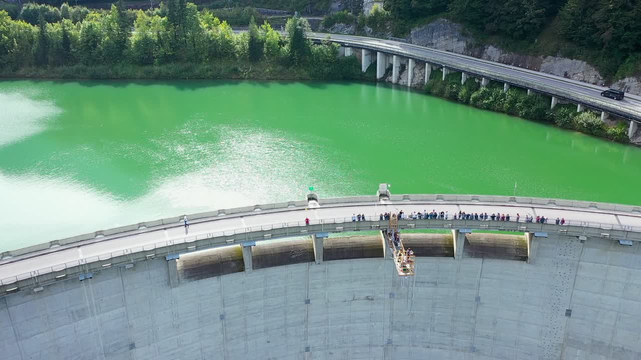 Viewers on bridge watching people bungee jumping off a high dam platform in Austria