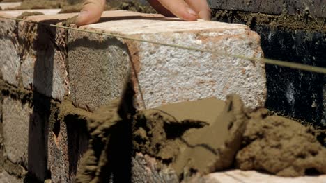 close up, brick placed on even wet mortar cement during house construction