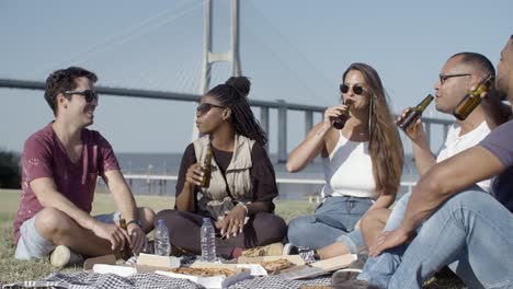 Relaxed-young-people-clinking-beer-bottles-in-park.