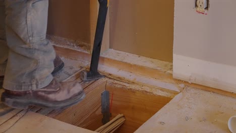 construction worker kicking and prying wood