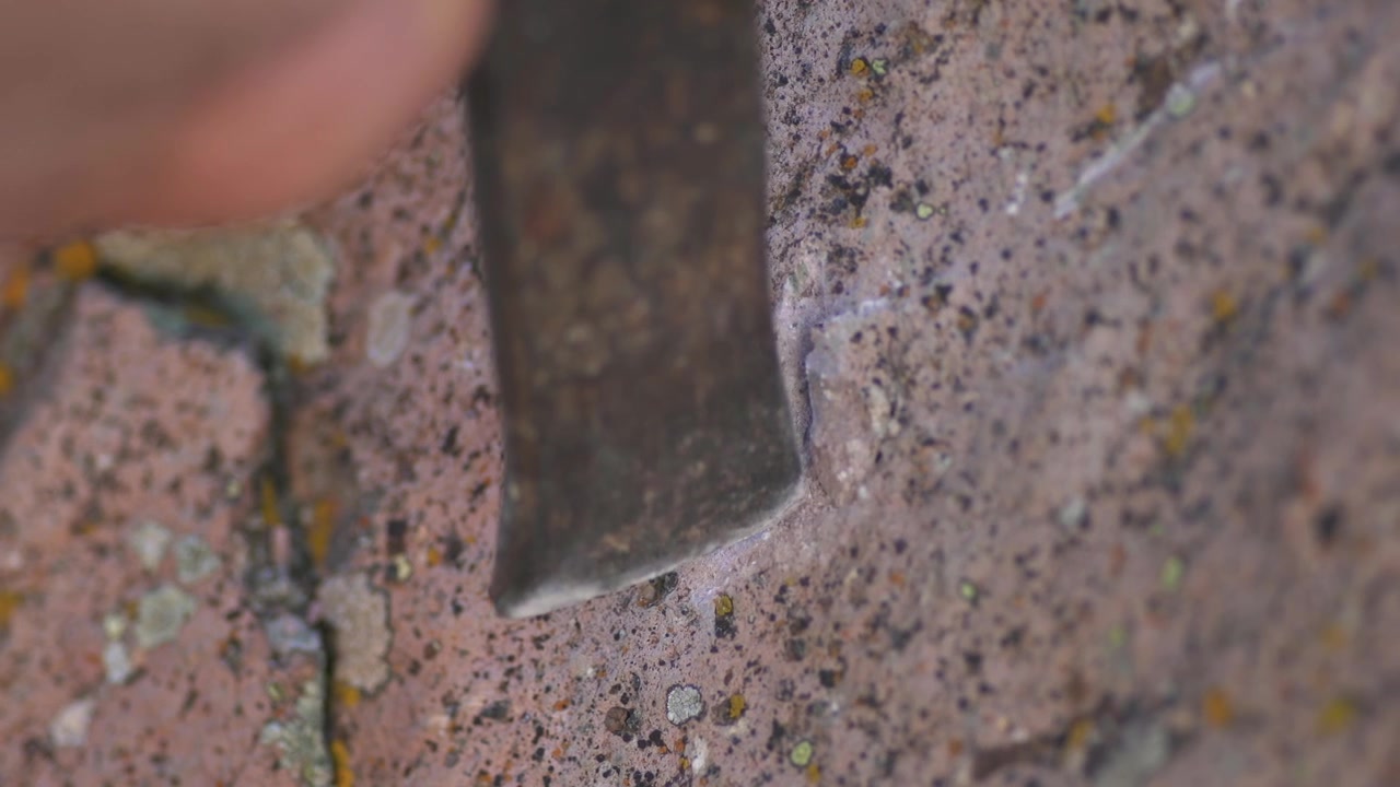 Geologist Using Chisel to Extract Mineral Sample from Rock