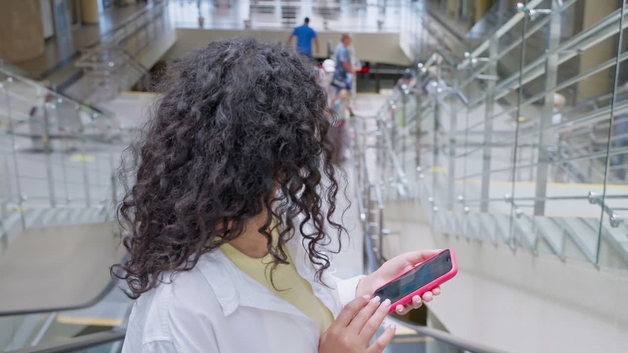 Woman using phone at airport terminal escalator