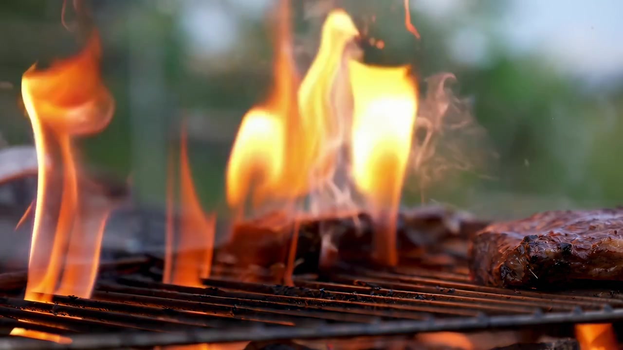Squisita carne che sfrigola sulla griglia del barbecue con fiamme intense