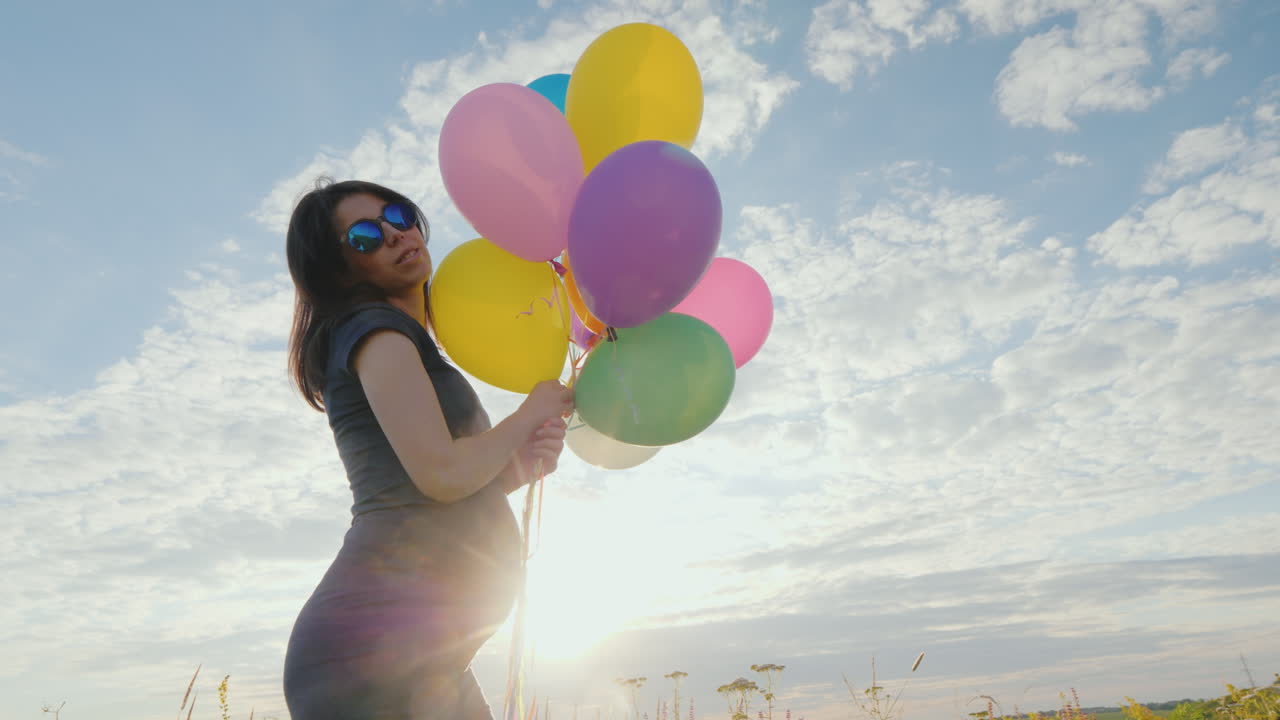 푸른 하늘을 배경으로 풍선을 가지고 노는 행복한 임산부
