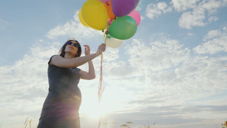 Feliz-Mujer-Embarazada-Jugando-Con-Globos-Contra-El-Cielo-Azul