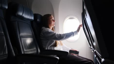 woman looking at smart monitor on airplane, lost in her thoughts of travel, reflections and adventures