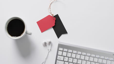 video of computer keyboard, cup of coffee, earphones, gift tags with copy space on white background