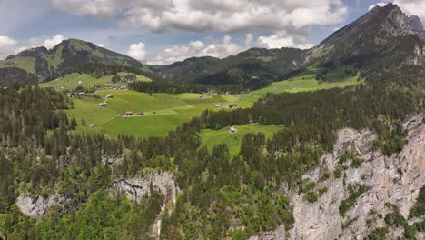 aerial view of seerenbachfälle waterfall near amden, with meadows and alpine houses above rocky cliffs in switzerland.