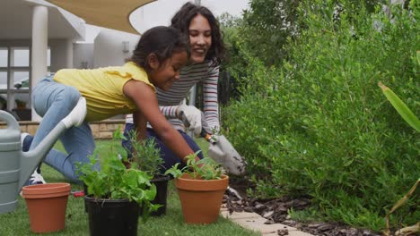Hispanic-mother-and-daughter-teaching-planting-flowers-in-the-garden