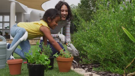 hispanic mother and daughter teaching planting flowers in the garden