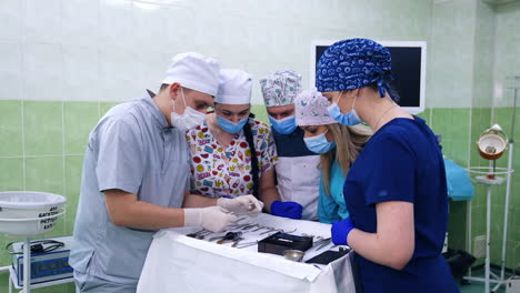 male medic teacher showing the metal tools used in dentistry to the students. future dentists compare two instruments.