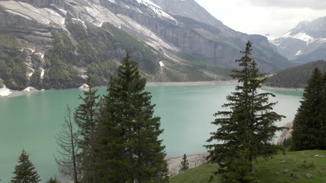 flying through two fir trees towards the oeschinensee in the oeschinen valley of switzerland