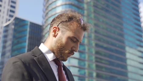 Joven-Empresario-Hablando-Por-Teléfono-Entre-Grandes-Edificios.