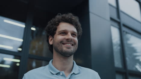 Portrait-smiling-man-posing-at-modern-building.-Teacher-welcoming-pupils-closeup