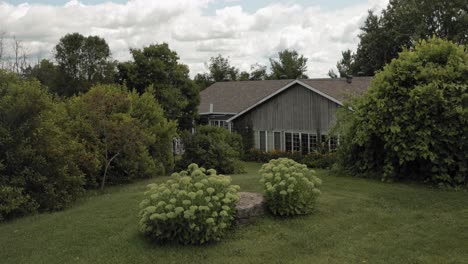 revealing a beautiful grey wood sided mansion from a water fountain feature in the garden of the acreage at the strathmere wedding and event centre