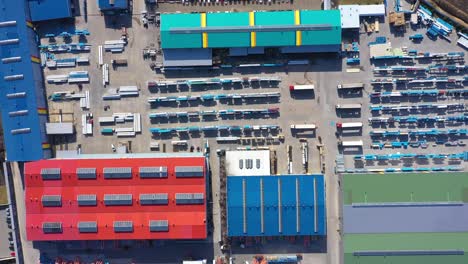 Aerial-view-of-a-semi-trucks-with-cargo-trailers-standing-on-warehouses-ramps-for-loading-unloading-goods-on-the-big-logistics-park-with-loading-hub