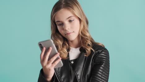 una adolescente caucásica con una chaqueta de cuero usando su teléfono inteligente.