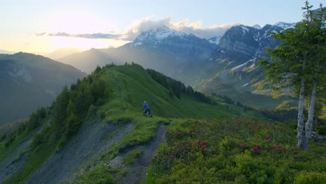 mountain biker rides down an alpine ridge at sunrise