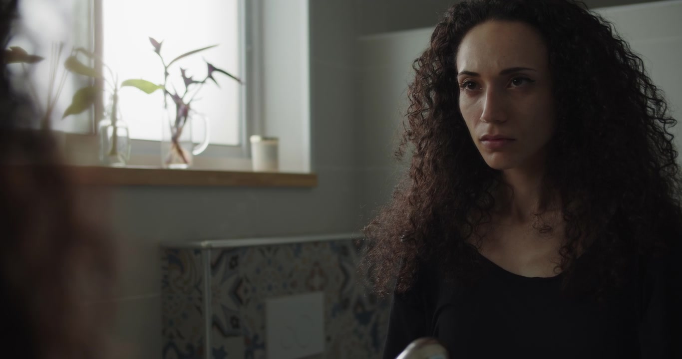 A curly haired woman looking at herself