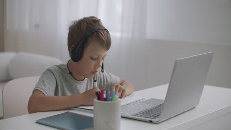 little-boy-is-sitting-on-couch-at-home-and-using-video-call-for-communicating-with-friends-by-laptop-self-isolation