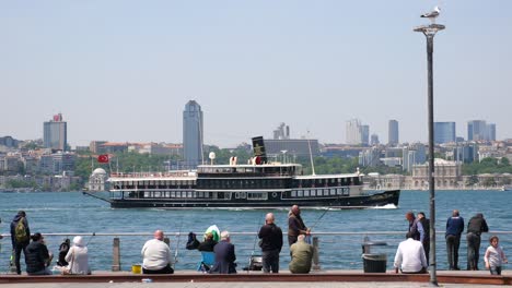 people fishing by the water with a boat and a city skyline in the background