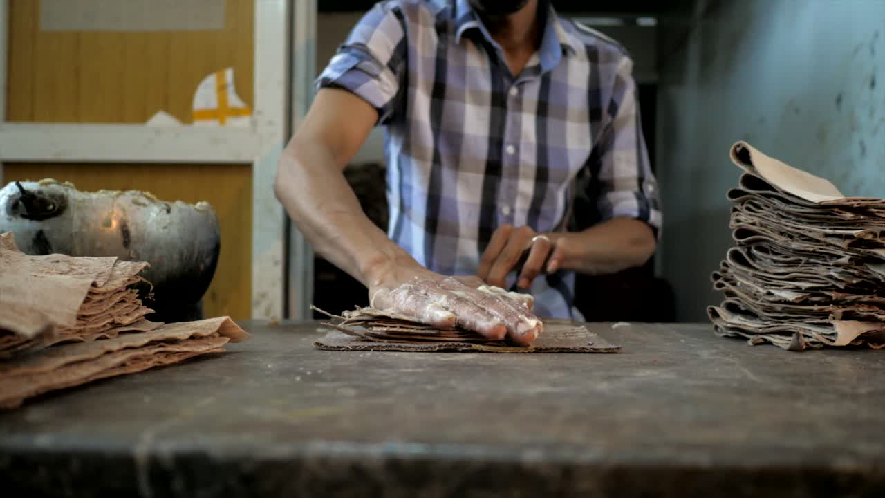 trabajador aplicando pegamento en pequeñas piezas de prendas de cuero en la fábrica