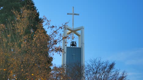 cross atop bell tower of a church in autumn in east vancouver, bc, canada