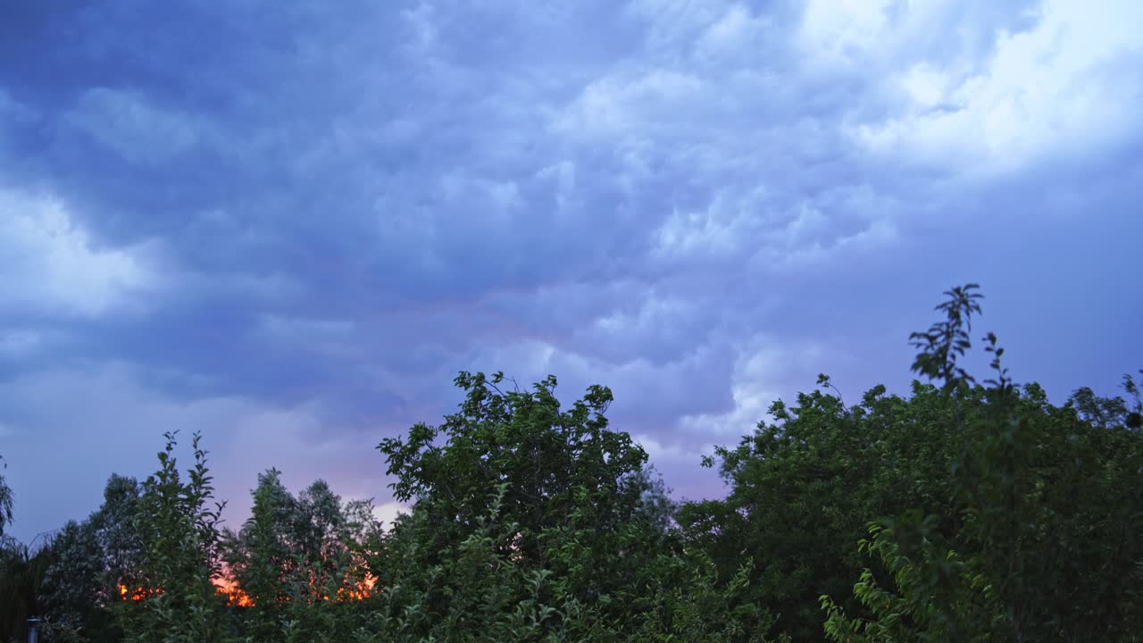 Lightning on the cloudy sky in summer. Strong and impressive lightning on the sky with bright clouds over the top of green trees.