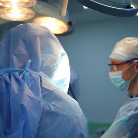 teamwork of surgeons. doctor in medical mask and glasses. group of medical workers in protective suits perform an operation.