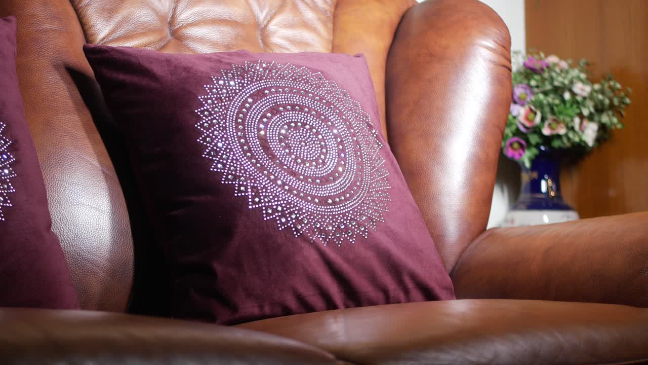 Embellished Purple Pillow on Brown Leather Sofa