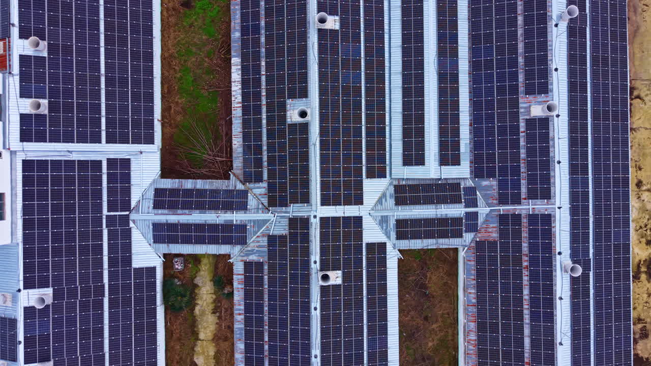 Grande installazione di pannelli solari sul tetto di un edificio in una zona rurale, catturata dall'alto durante le ore diurne