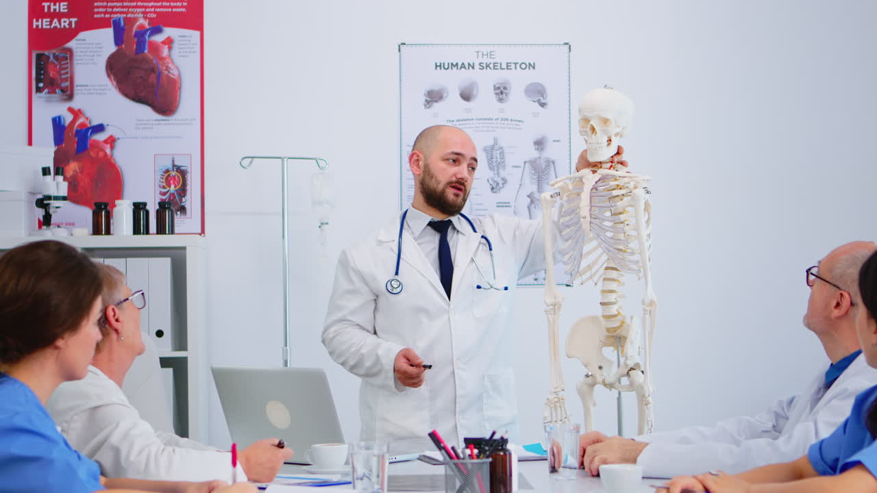 Medico che indica la colonna vertebrale cervicale di uno scheletro umano.