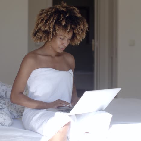 young woman using laptop on bed