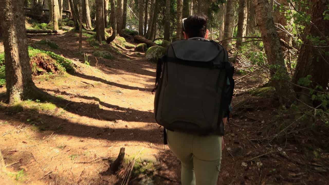 mujer caminando con una mochila de senderismo en el bosque verde de primavera
